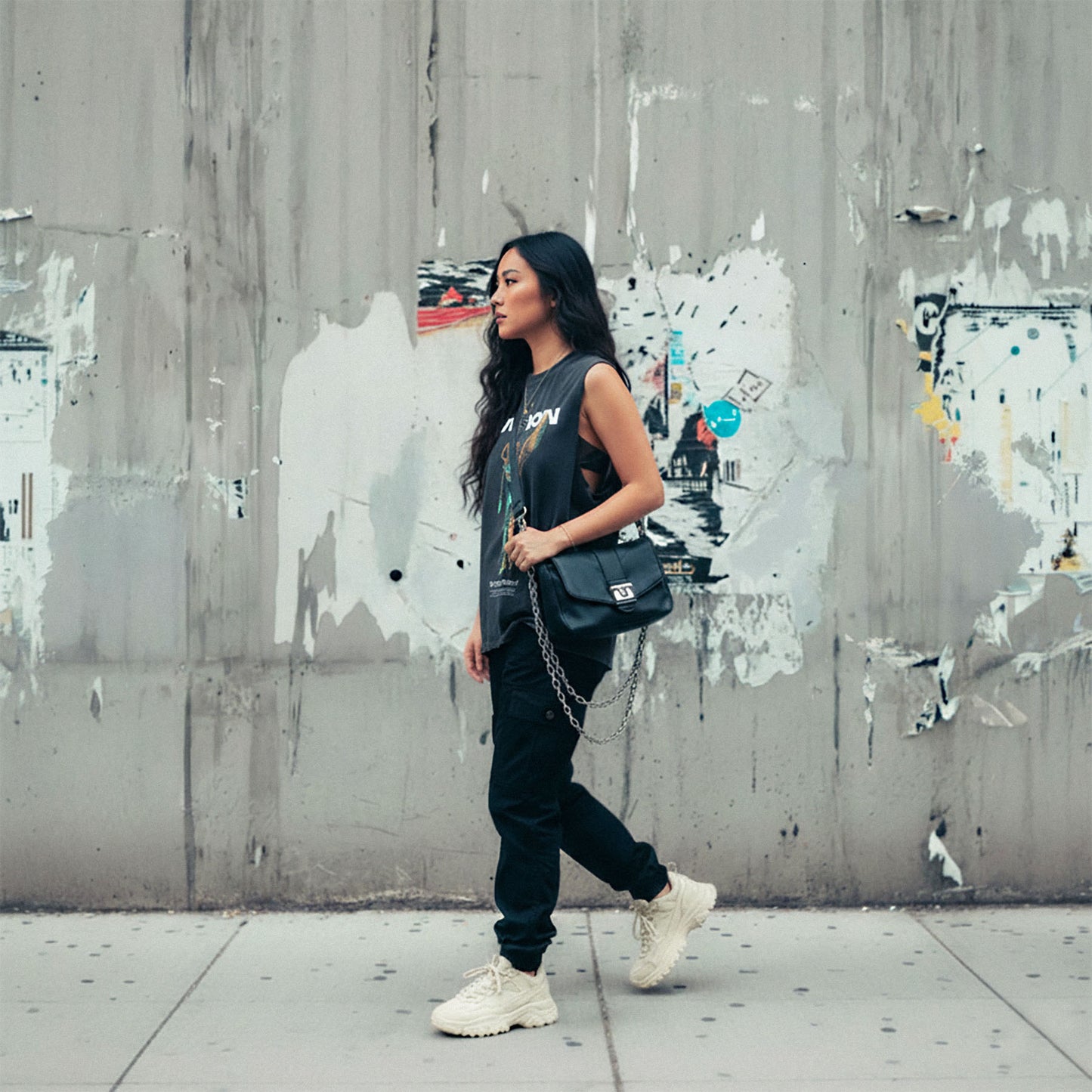 Woman walking against a textured wall with graffiti