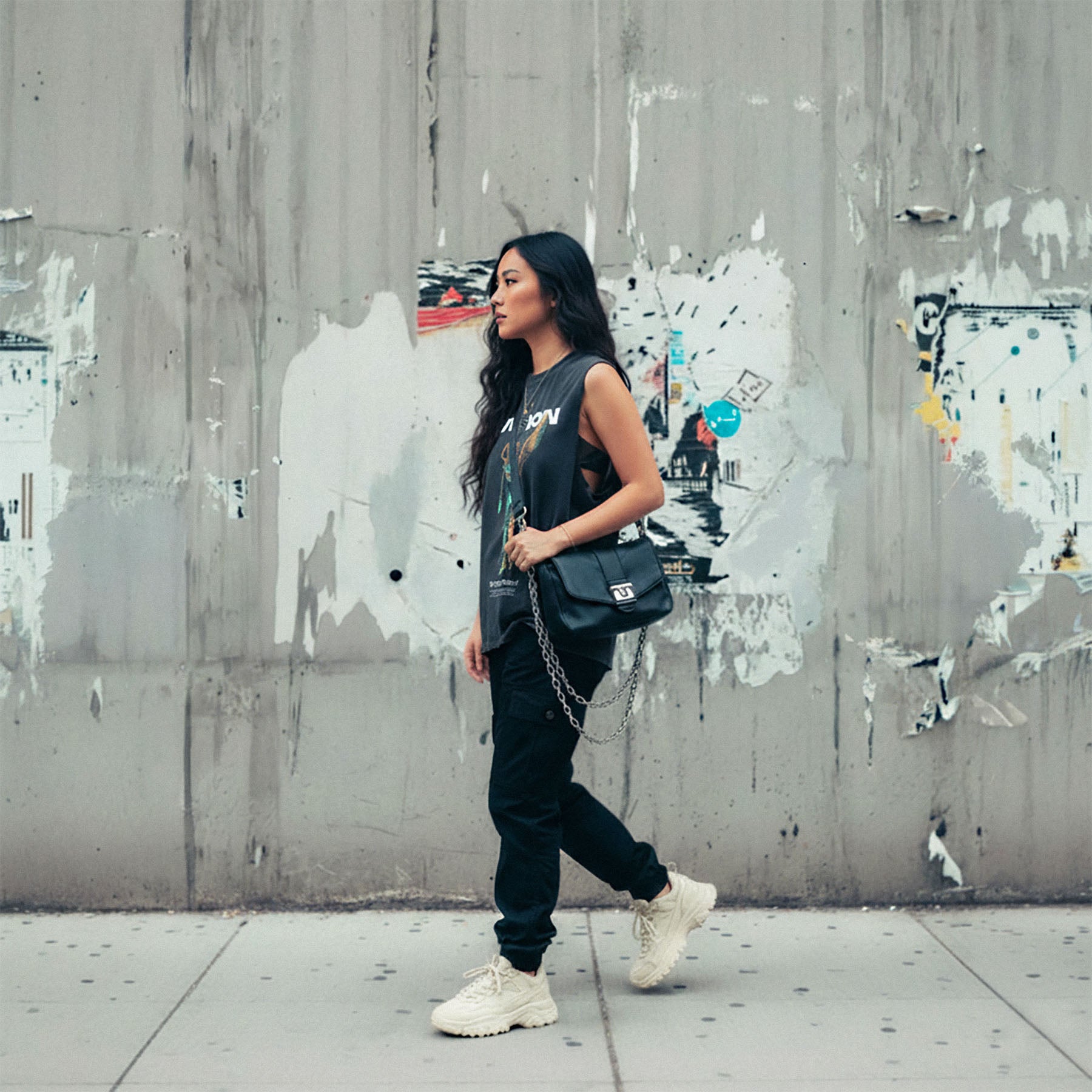 Woman walking against a textured wall with graffiti