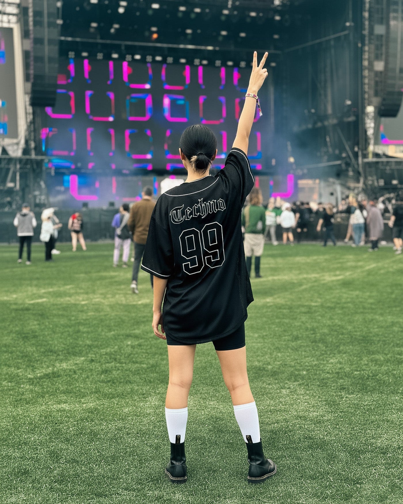 Person in a black sports jersey with '99' on a grassy field with a large screen displaying colorful graphics in the background.
